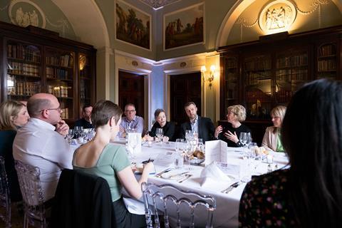 11 attendees sit around a large oval-shaped table engaging in a roundtable discussion on insurance fraud.